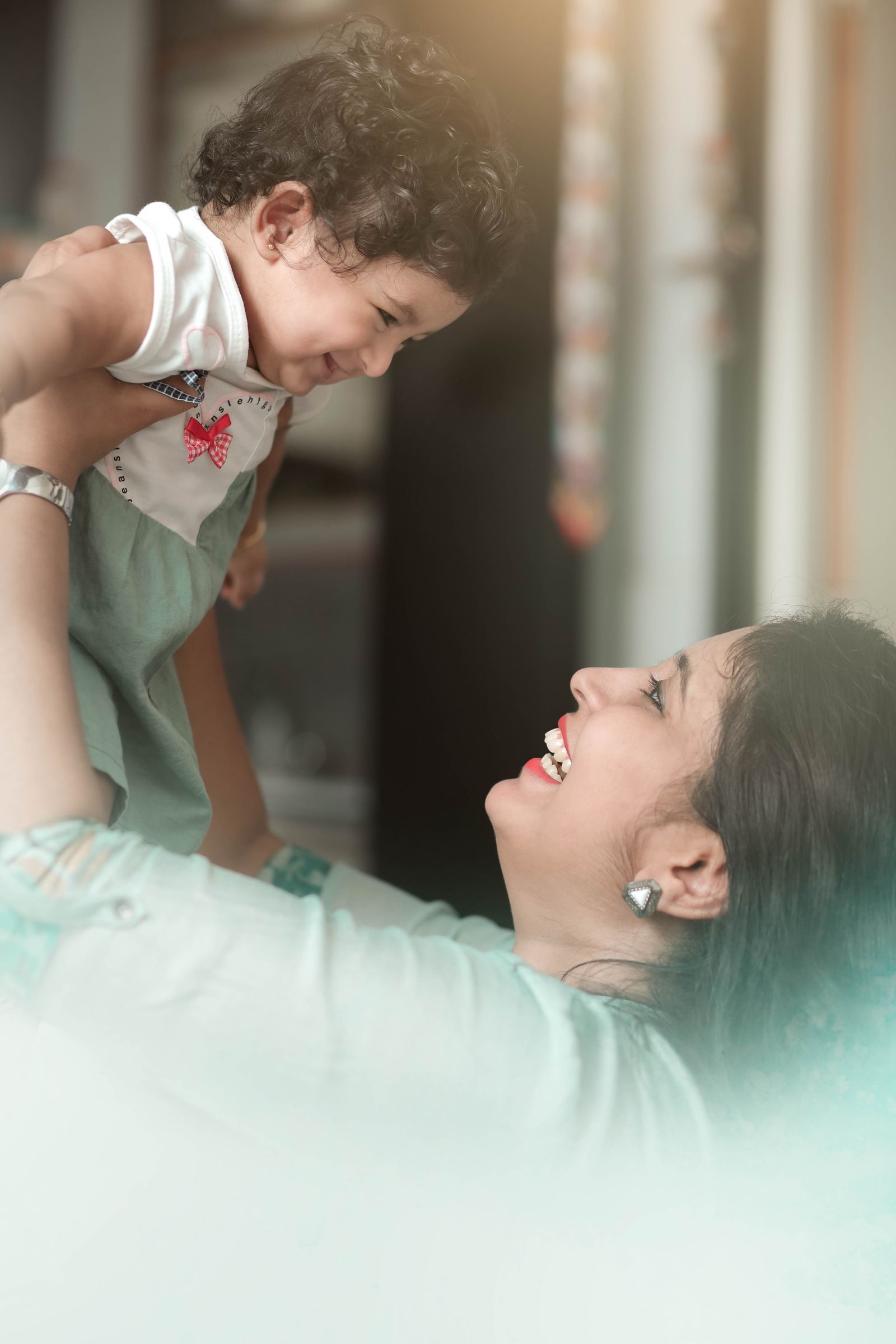 A mother lifting her laughing toddler
